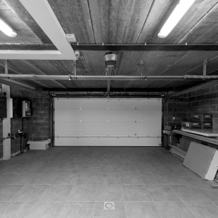 Intérieur d'un garage vide avec porte sectionnelle, photo en noir et blanc.