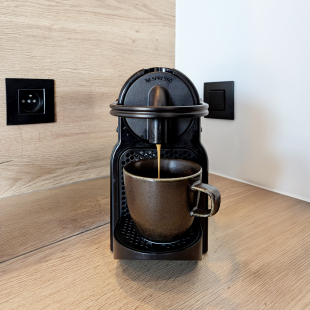 Machine à café Nespresso en train de préparer un café sur un plan de travail en bois.