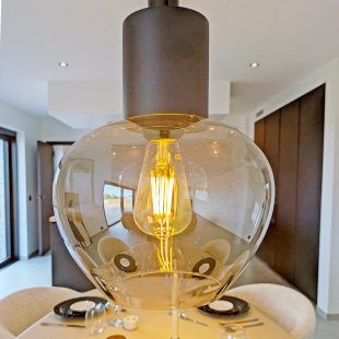 Suspension luminaire allumée au-dessus d'une table dressée pour un repas.